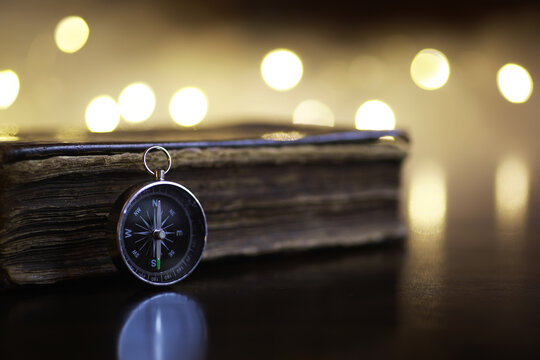 Vintage Compass on Antique Book with Warm Bokeh Lights Background - Exploration and Navigation Concept