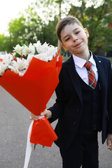 Naklejka premium Young Schoolboy in Suit Holding Bouquet of Flowers Outdoors Ready for Celebration