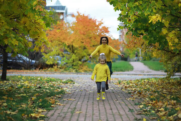 Fototapeta premium Mother and Daughter Walking in Park During Autumn Season in Yellow Outfits