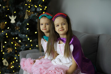 Naklejka premium Twin Girls in Costume Near Christmas Tree