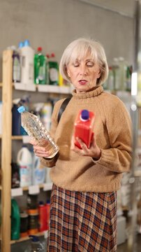 Mature housewife carefully selects safe stain remover in supermarket. High quality 4k footage