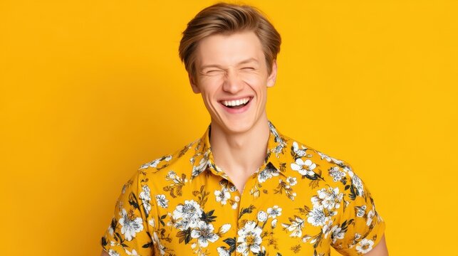 Young man smiling brightly in a floral shirt against a vibrant yellow background exuding happiness and positivity