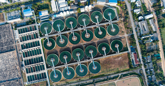 Wastewater treatment plant aerial view, circular tanks and large reservoirs in industrial facility, environmental engineering and sustainability concept, wide angle with natural lighting.