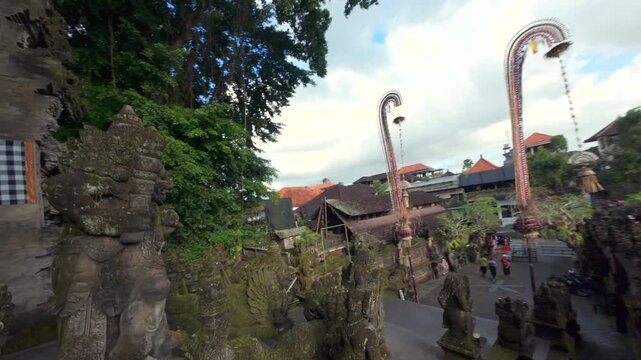 Cinematic FPV view of ornate Balinese temple entrance in Ubud, Bali, with moss-covered stone carvings, statues, and traditional architecture.