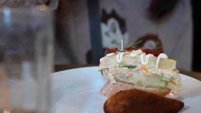 A woman eating pinchos, a famous tapas dish from Spain's Basque Country 　