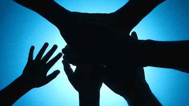 Silhouetted hands overlap against a luminous blue background, forming a shared focal point