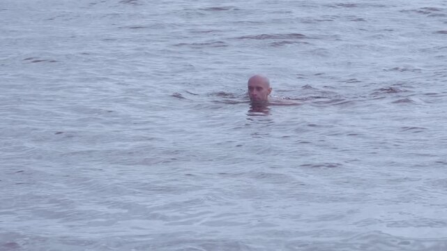 young man swims in sea, ocean, aquatic adventure, man immersed in seawater feels rush of waves filling his ears, risks and dangers swimming in open water, drowning hazard, ear infection