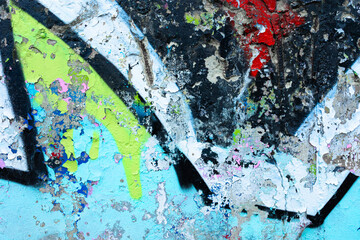 Fototapeta premium Weathered concrete wall with distressed blue peeling paint and spray paint fragments. Aged urban surface with substrate texture and paint erosion for street art backgrounds and grunge designs.