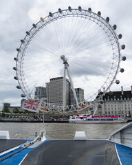 Fototapeta premium London, United Kingdom, 13 July 2023, The London Wheel rises above the Thames in central London. A river vessel passes below the wheel during daytime.