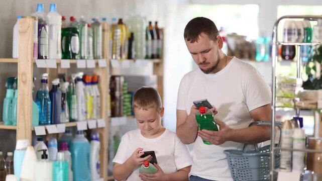  Young man with his son buyers scanning qr code for dishwashing detergent in household chemicals store 