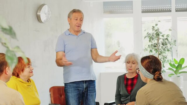 Enthusiastic elderly male tutor talking to group of older adults during educational class. Concept of new experiences and knowledge in advanced years. High quality 4k footage