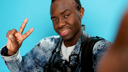 Photographer taking selfies and fooling around in front of camera, doing peace sign and showing...