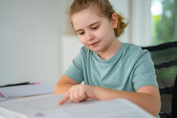 Naklejka premium Kid reading a book at home. Child enjoying storybook in cozy room. Little boy reading books in bedroom. Cute girl reading favorite story at home. Young kid learning with book in living room.