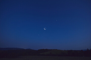 Fototapeta premium Morning old Moon with stars, planets and rural countryside tree silhouettes.