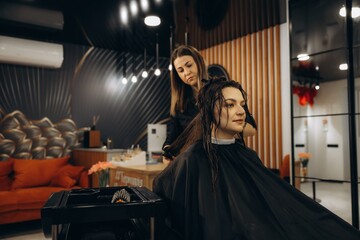Fototapeta premium Hairdresser styling woman's wet hair in salon