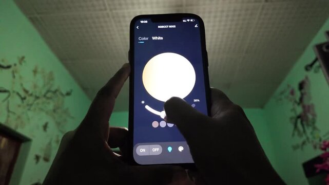 Close-up of a person adjusting smart bulb brightness using a mobile app. Modern home automation concept with real-time lighting control, minimal indoor setting, and practical everyday technology use.