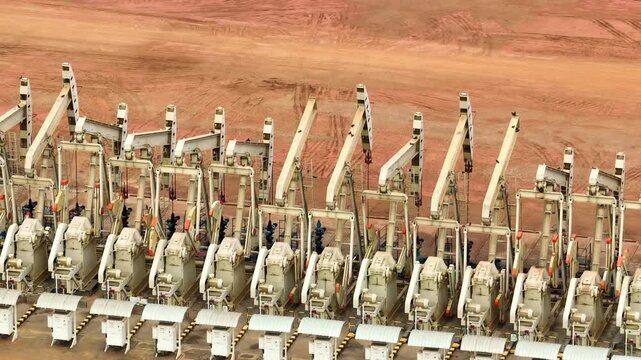 Aerial drone view of multiple oil pumpjacks operating in a vast field, reflecting global energy demand, supply resilience, and ongoing reliance on fossil fuels in today&rsquo;s volatile oil market.
