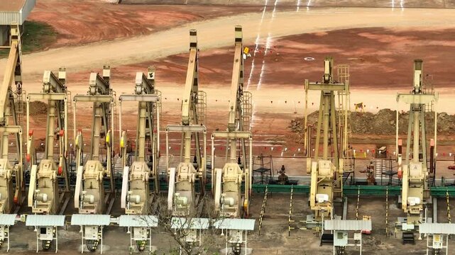 Close-range drone perspective of multiple oil pump jacks, representing global supply chains, geopolitical influence on oil prices, and the continued importance of petroleum in modern economies.
