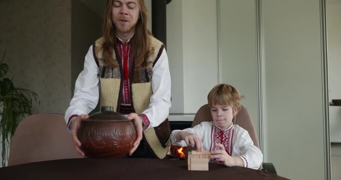 Kid Boy Waiting For Dinner. Man Serving Dishes on Table Family in Ukrainian Traditional Attire Childhood. 4K 10-bit