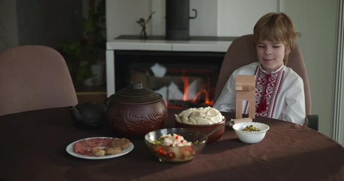 Kid Boy Waiting For Dinner. Man Serving Dishes on Table Family in Ukrainian Traditional Attire Childhood. 4K 10-bit