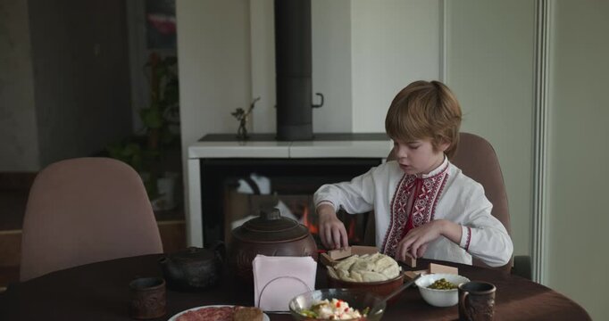 Kid Boy Waiting For Dinner. Man Serving Dishes on Table Family in Ukrainian Traditional Attire Childhood. 4K 10-bit
