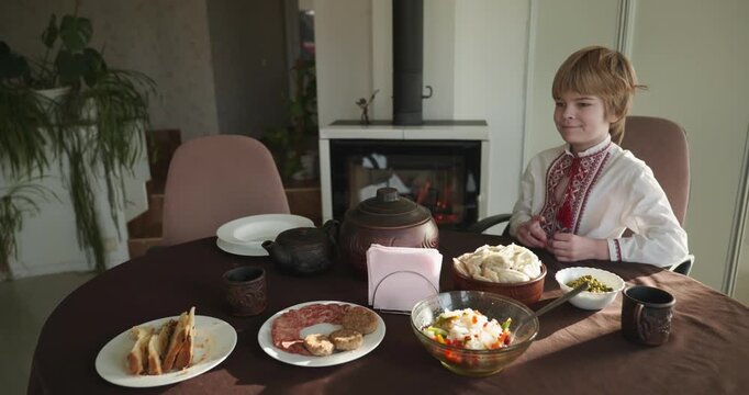 Kid Boy Waiting For Dinner. Man Serving Dishes on Table Family in Ukrainian Traditional Attire Childhood. 4K 10-bit