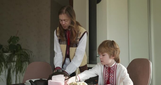 Kid Boy Waiting For Dinner. Man Serving Dishes on Table Family in Ukrainian Traditional Attire Childhood. 4K 10-bit