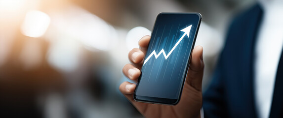 A close-up view of a hand holding a smartphone showing a clear rising financial trend line graph.