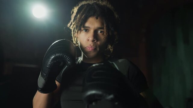 Self-defense and sport workout in fitness club, young african man fighting. Portrait of professional motivated sportsman practicing box and kickboxing, healthy lifestyle and combat sport for keep fit,
