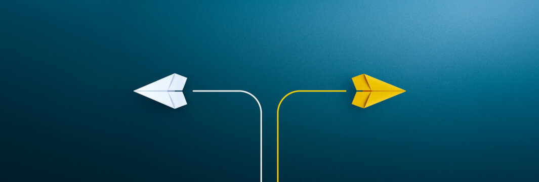 Two paper planes flying in opposite directions on blue background, concept of decision making and choosing different paths.
