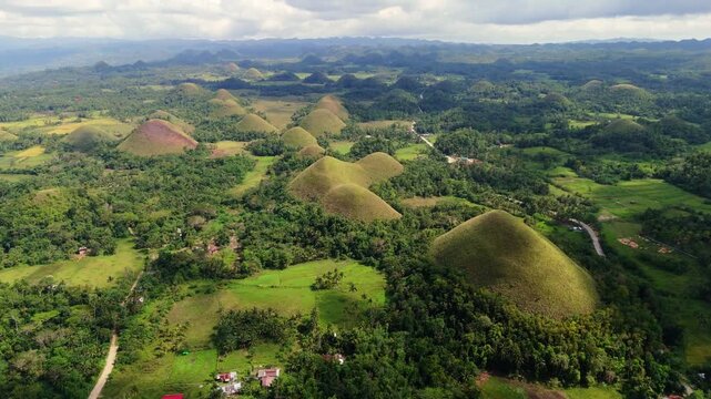 Aerial view of a winding road passing through the unique Chocolate Hills of Bohol, Philippines