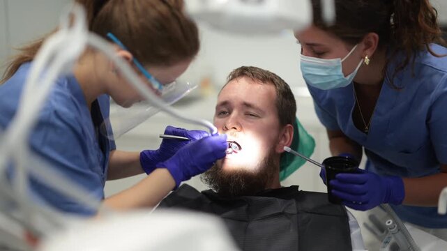Two female dentists treat man teeth at a dental clinic. High quality 4k footage