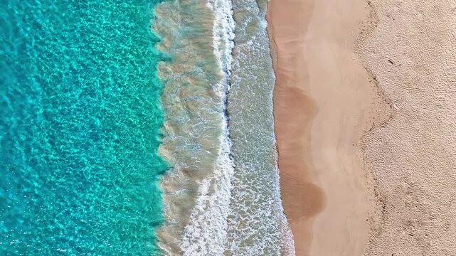 A backdrop of large ocean waves on a tropical sandy coastline. A soft blue ocean wave on a sandy tropical beach. A foamy sea wave crashes onto the shore. An empty tropical beach and seascape.