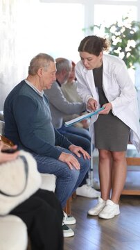 Nurse or doctor talk with elderly man in reception area . High quality 4k footage