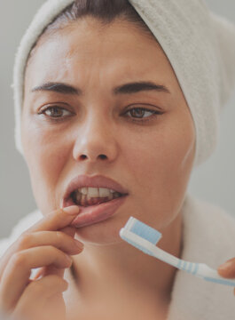 Young woman looking at her red bleeding gums	