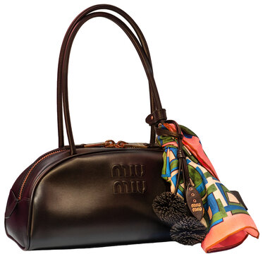 A shoulder bag with a rounded design, crafted from brown leather with charms and an embossed Miu Miu logo on the front. Milan - Italy,23 March 2026
