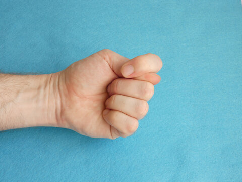 Male Hand Showing Fig Gesture Over Blue Felt