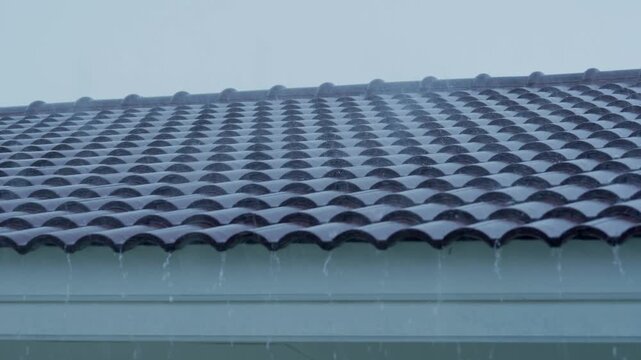 Intense rainfall cascading from a residential rooftop, illustrating shifting climate conditions, unpredictable storms, and the growing effects of global warming on everyday weather patterns.
