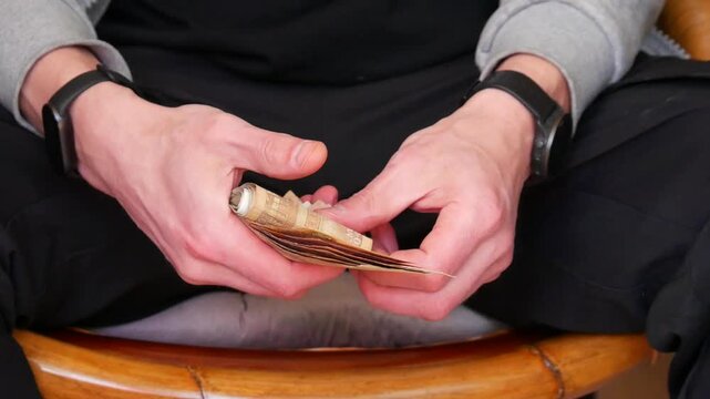 Man holding a stack of cash currency bills in his hands. Close up of male fingers counting banknotes. Financial management and wealth banking concept for economy.