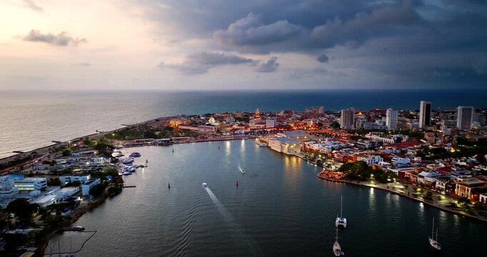 Drone view of the historic walled city and harbor of Cartagena with city lights at dusk, Colombia. Aerial, copy space