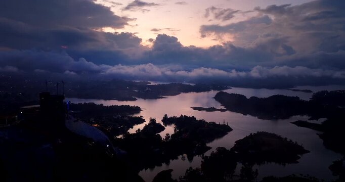 El Pe&ntilde;&oacute;n de Guatap&eacute; or Rock of Guatap&eacute; and the surrounding reservoir with islands under a dramatic sunset sky in Colombia. Aerial forward, copy space