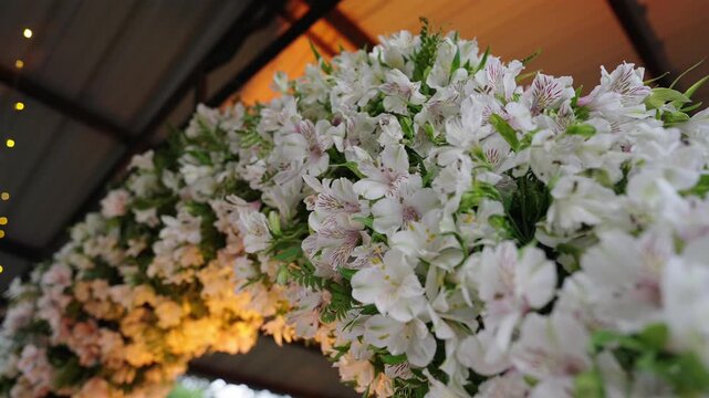 Close-up rotating reveal of a wedding arch decorated with white alstroemeria, spray roses and delicate filler flowers with greenery, showcasing texture, layering and elegant floral design