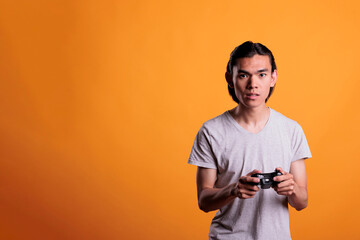 Young asian man playing video games with wireless gamepad, leisure activity, fun pastime. Teenager holding console controller gadget in hands, enjoying videogames with joystick © DC Studio