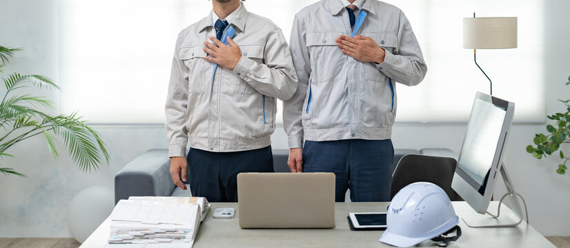 胸に手を当てる作業服を着た男性