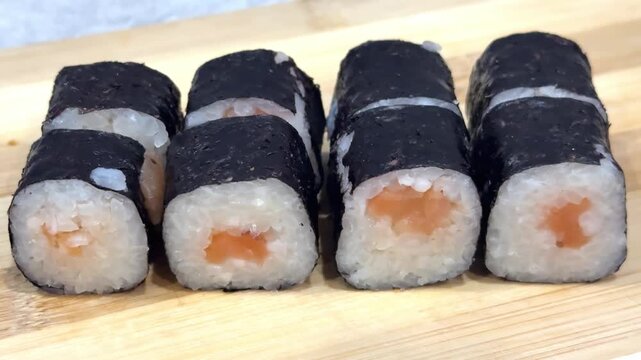 Delicious traditional japanese sushi maki rolls with salmon and rice wrapped in nori seaweed. Healthy asian food on a wooden platter