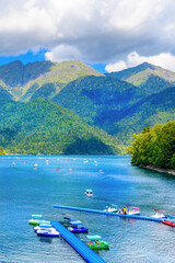 Fototapeta premium Scenic view of Lake Ritsa with mountains and paddle boats, Abkhazia.A popular tourist destination in the Ritsa National Park.