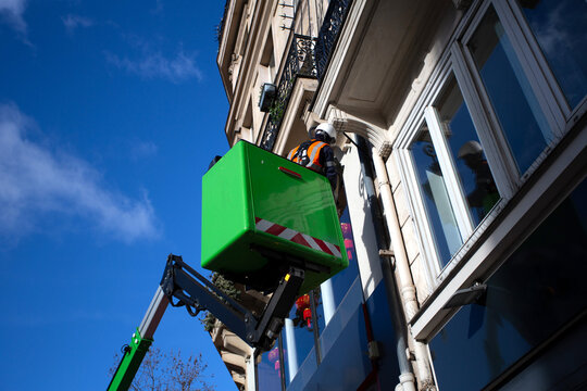 Ouvrier dans une nacelle t&eacute;lescopique qui r&eacute;pare un lampadaire &agrave; Paris