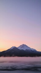 Fototapeta premium Snow-capped mountains at sunrise with misty lake dawn