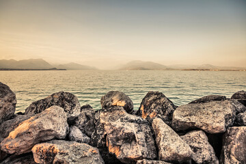 A romantic view of the lake at sunset. The shoreline is lined with huge rocks.