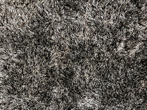 Close up of carpet rug flooring in black tuft color. Fabric with feather and fur in brown color. Seamless modern minimalist rug texture with tufted fur. Suitable for living room floor.